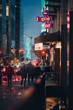 Bustling city street at night with neon lights and people walking, capturing urban nightlife energy.