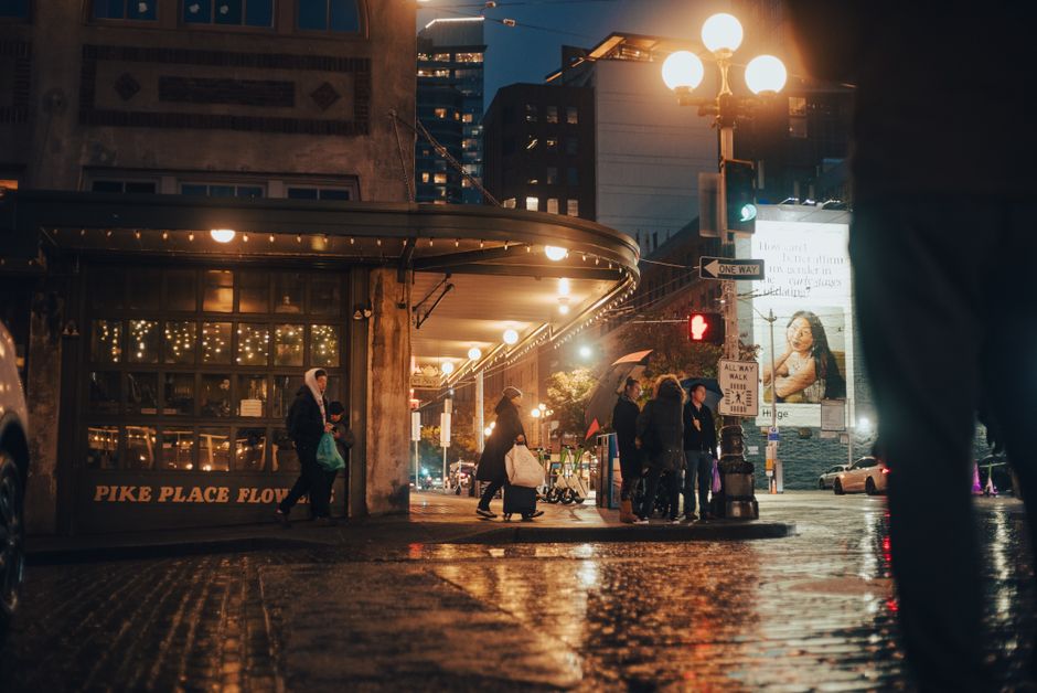 Bustling street scene at Pike Place Market at night with people and illuminated lights.