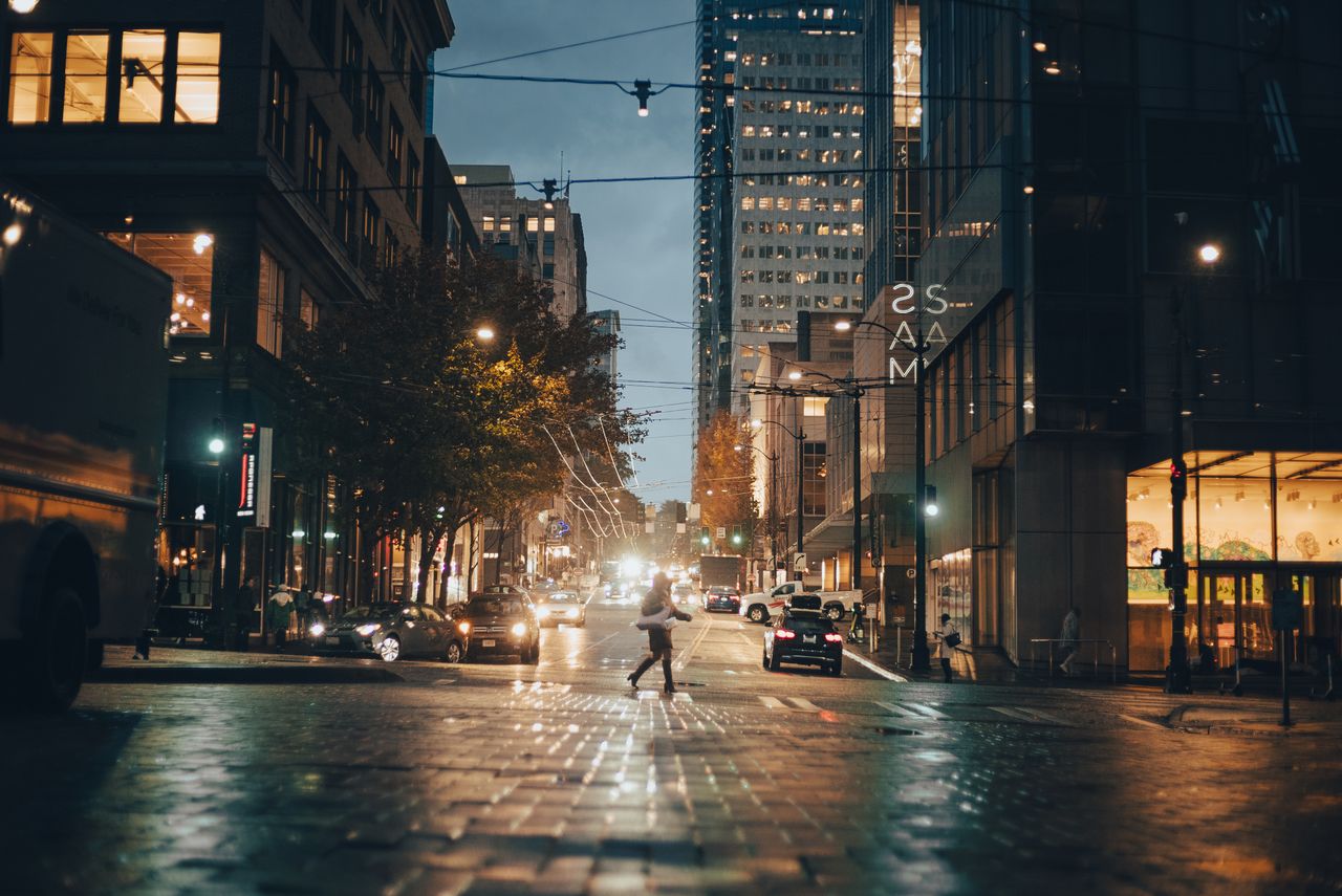 a bustling city street at night featuring illuminated buildings and ca