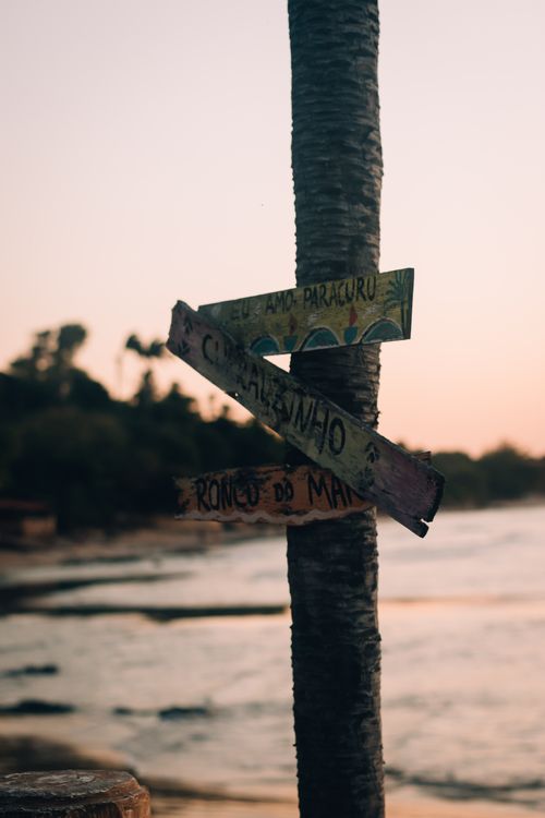 Free Colorful wooden signpost on Paracuru Beach, Brazil, during a serene sunset, capturing coastal charm. Stock Photo