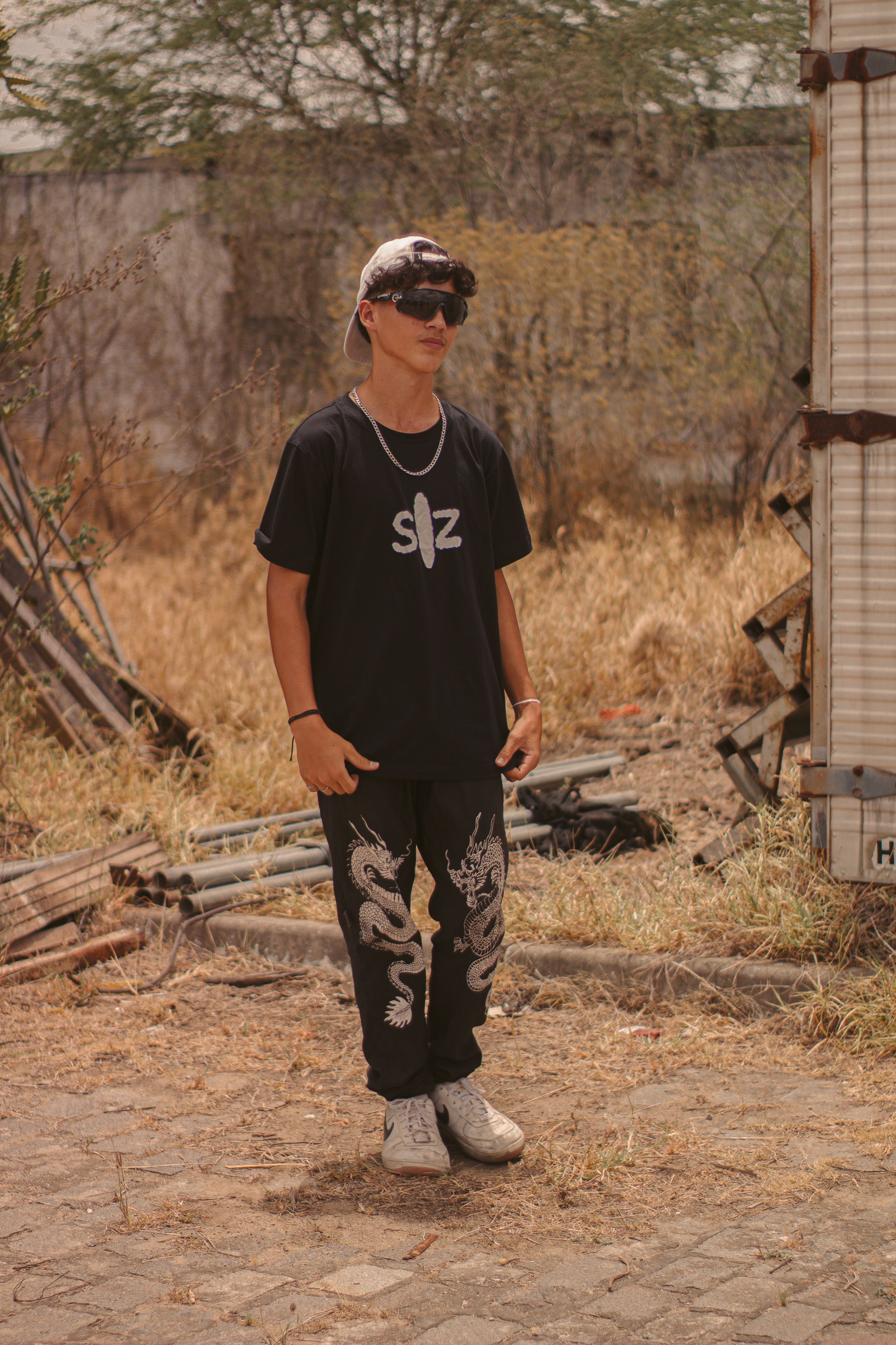Teen in a casual outfit with sunglasses posing outdoors on pavement.