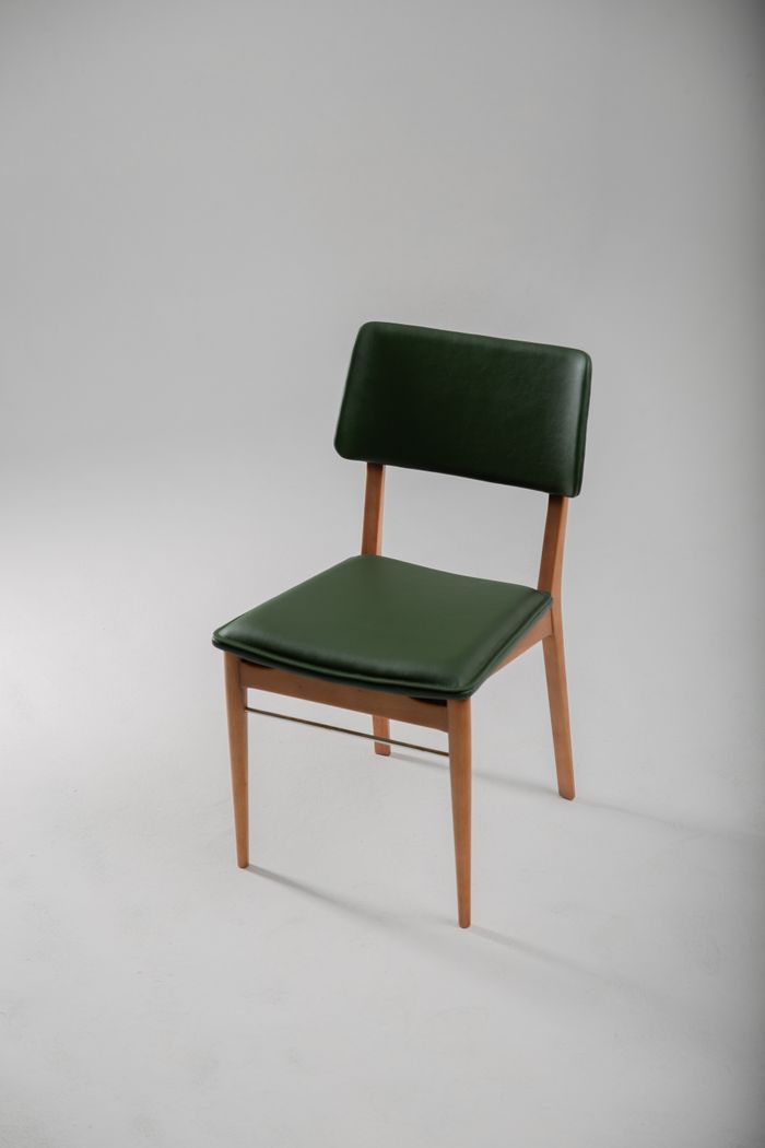 Retro wooden chair with a green cushion on a pale backdrop — photo by Sandro Tavares on Pexels