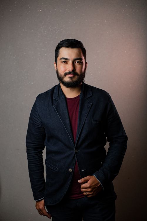 Free Studio portrait of a bearded man in a dark blazer standing confidently against a textured background. Stock Photo