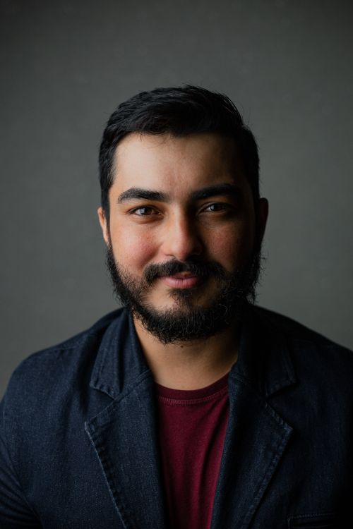 Free Portrait of a confident bearded man wearing a blue blazer against a gray background. Stock Photo