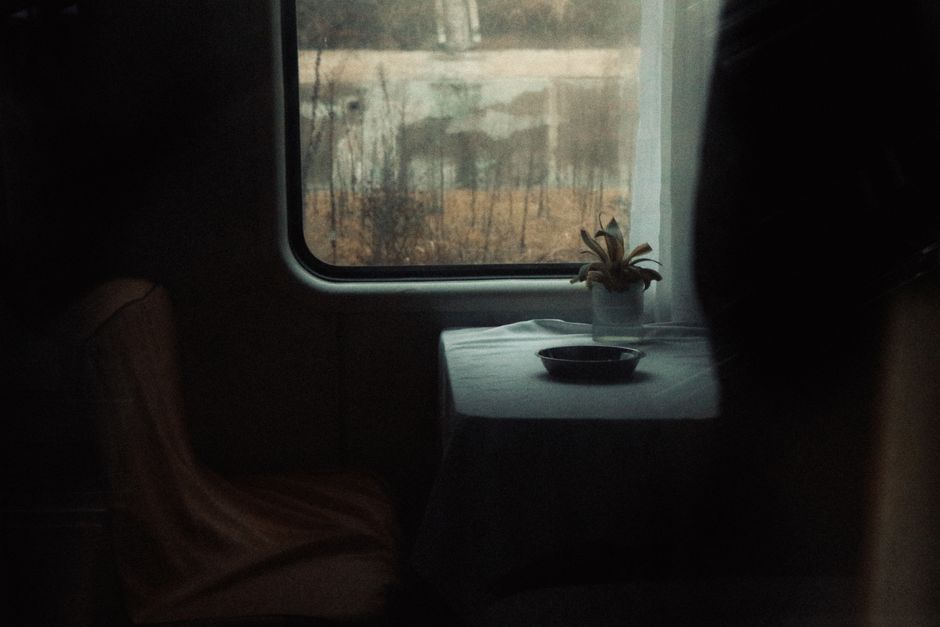 A serene and moody interior showing a table by a window with a potted plant.