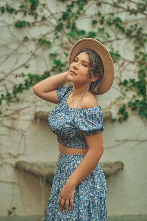 Free Elegant woman in floral dress wearing a hat, posing outdoors. Perfect for fashion and lifestyle themes. Stock Photo