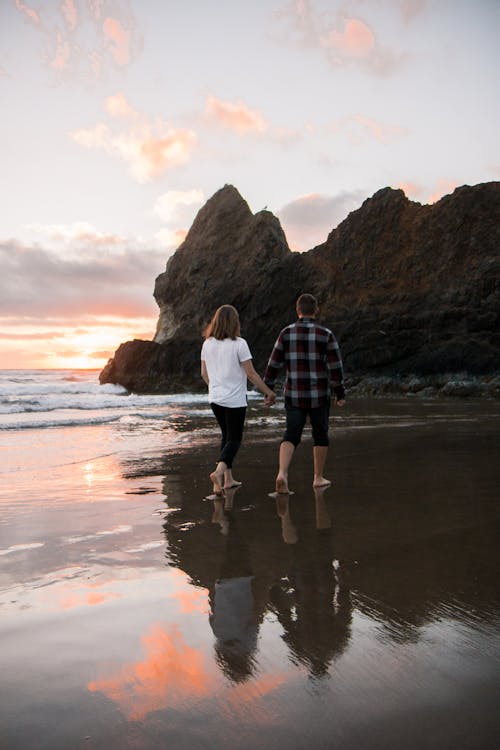 Free Man and Woman Walking on Beach Shore Stock Photo