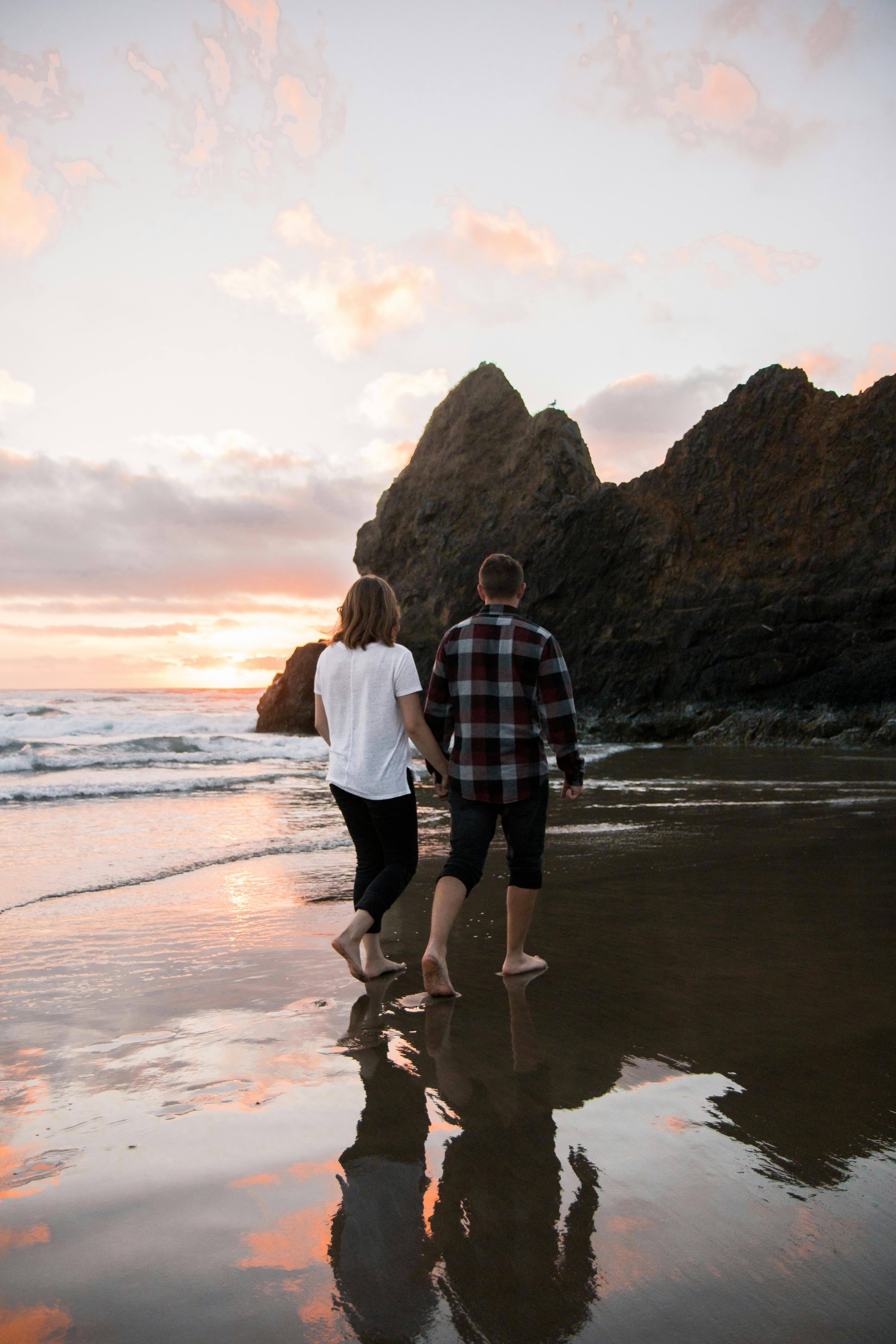 Couple walking along a beach at sunset, reflecting romance and tranquility.