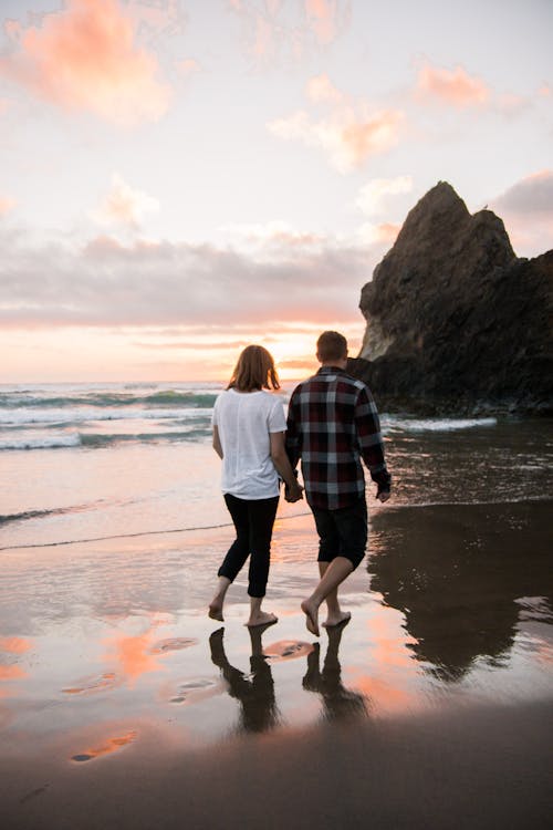 무료 손을 잡고 해변에 산책하는 커플 스톡 사진