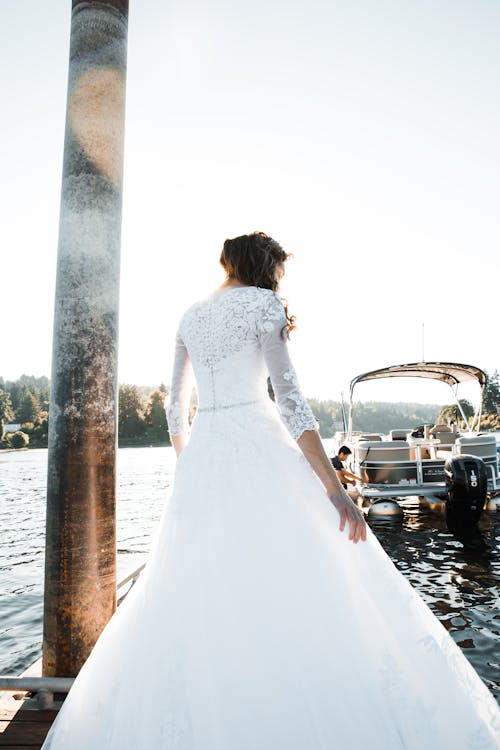 Woman in White Wedding Gown Standing Near Body of Water