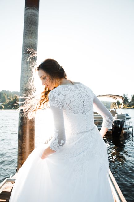 A serene lakeside moment featuring a bride in a lace wedding gown, softly illuminated by sunlight.