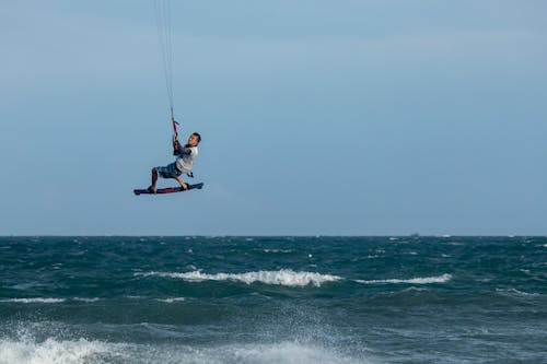 A Man Wearing a White Shirt Riding a Kite Board on a Blue Wavy Body of Water