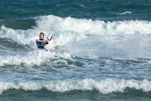 Man in a White Shirt Kitesurfing near Waves