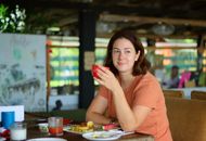 A woman with brown hair enjoys a drink at a cozy indoor café, exuding leisure and comfort.