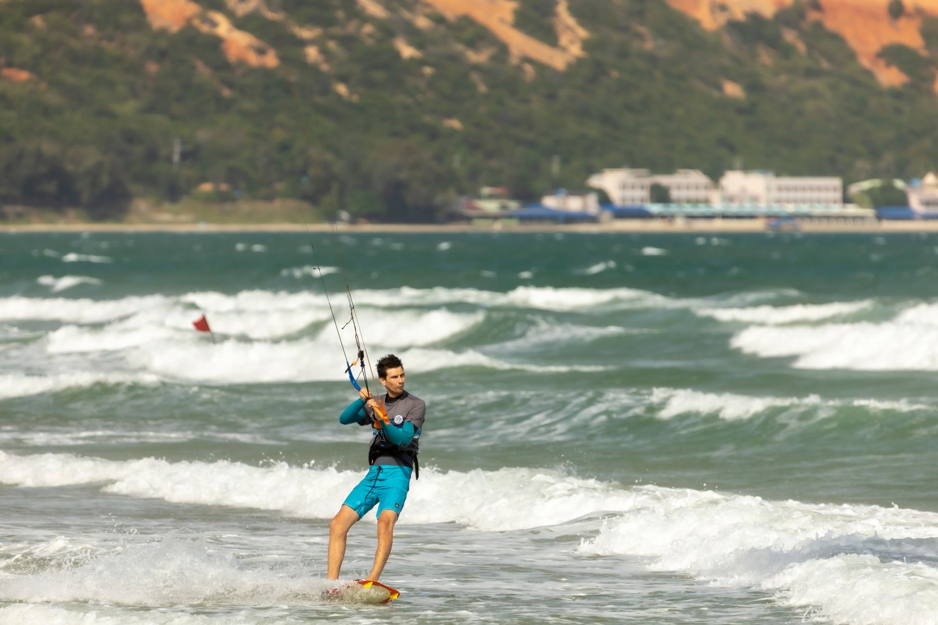 Man kitesurfing in sunny ocean with waves, capturing adventure and thrill of water sports.