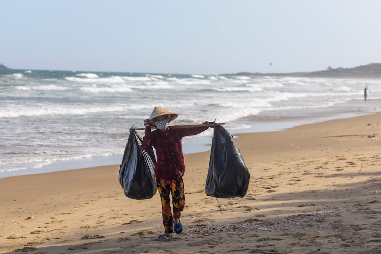 Person Carrying Garbage Bags Walking On The Breach