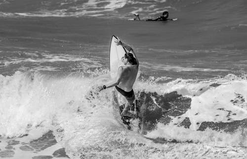 Grayscale Photo of Man Riding over Surfboard on Sea Waves