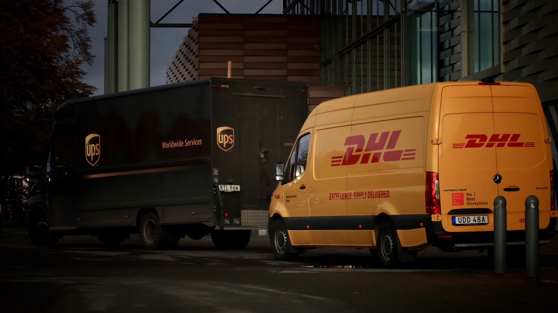 Modafinil Delivery to Canada: Comprehensive Guide DHL and UPS delivery trucks parked at night near a modern building, ready for logistics operations — modafinil delivery to canada
