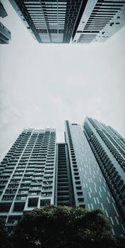Low angle shot of towering skyscrapers with a moody sky, highlighting urban architecture.