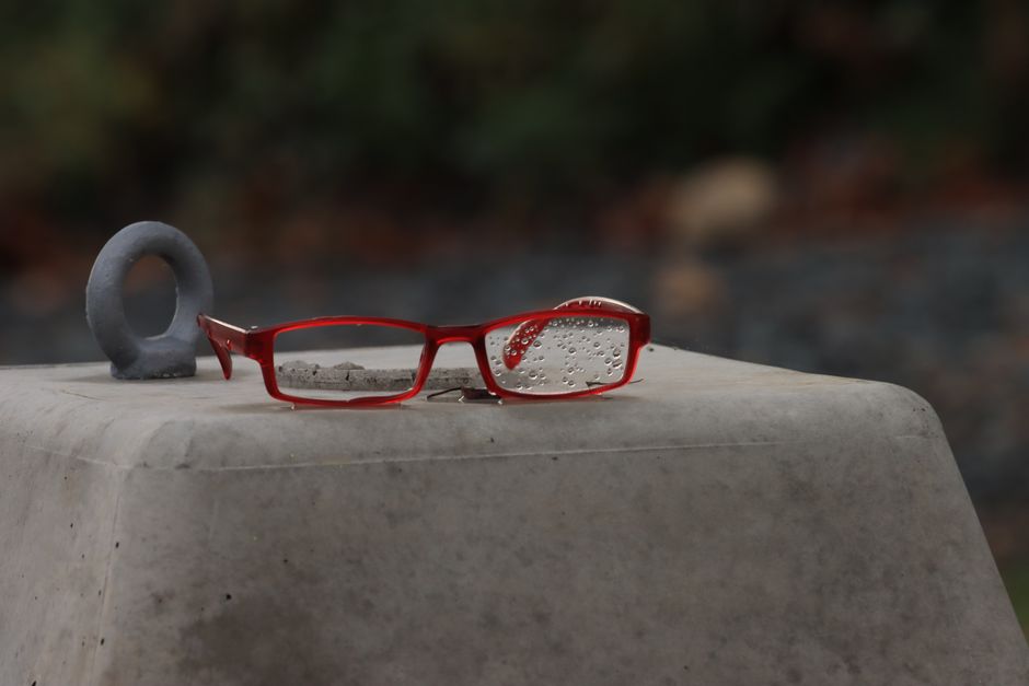 Red eyeglasses with raindrops on a concrete surface outdoors. Capturing serenity.