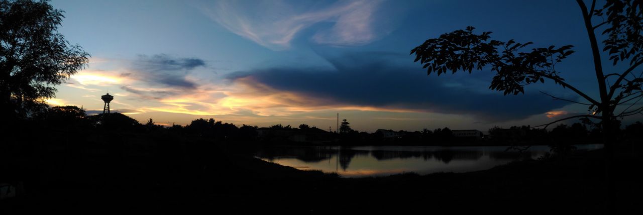 a tranquil sunset over a lake with silhouettes of trees and a tower