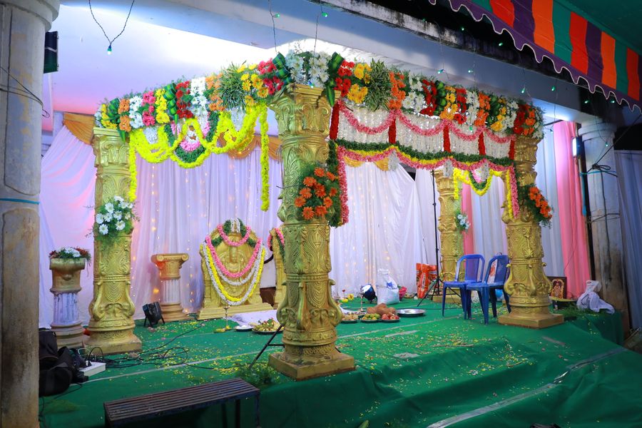 Vibrant wedding stage with golden columns and flower garlands