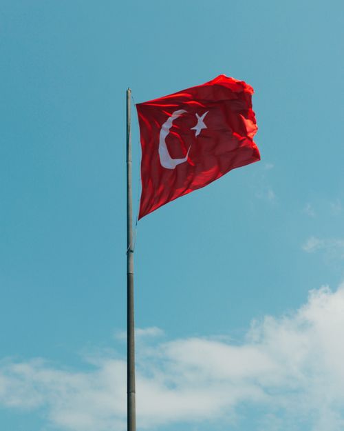 Free Turkish national flag waving high on pole under a clear, sunny sky. Stock Photo