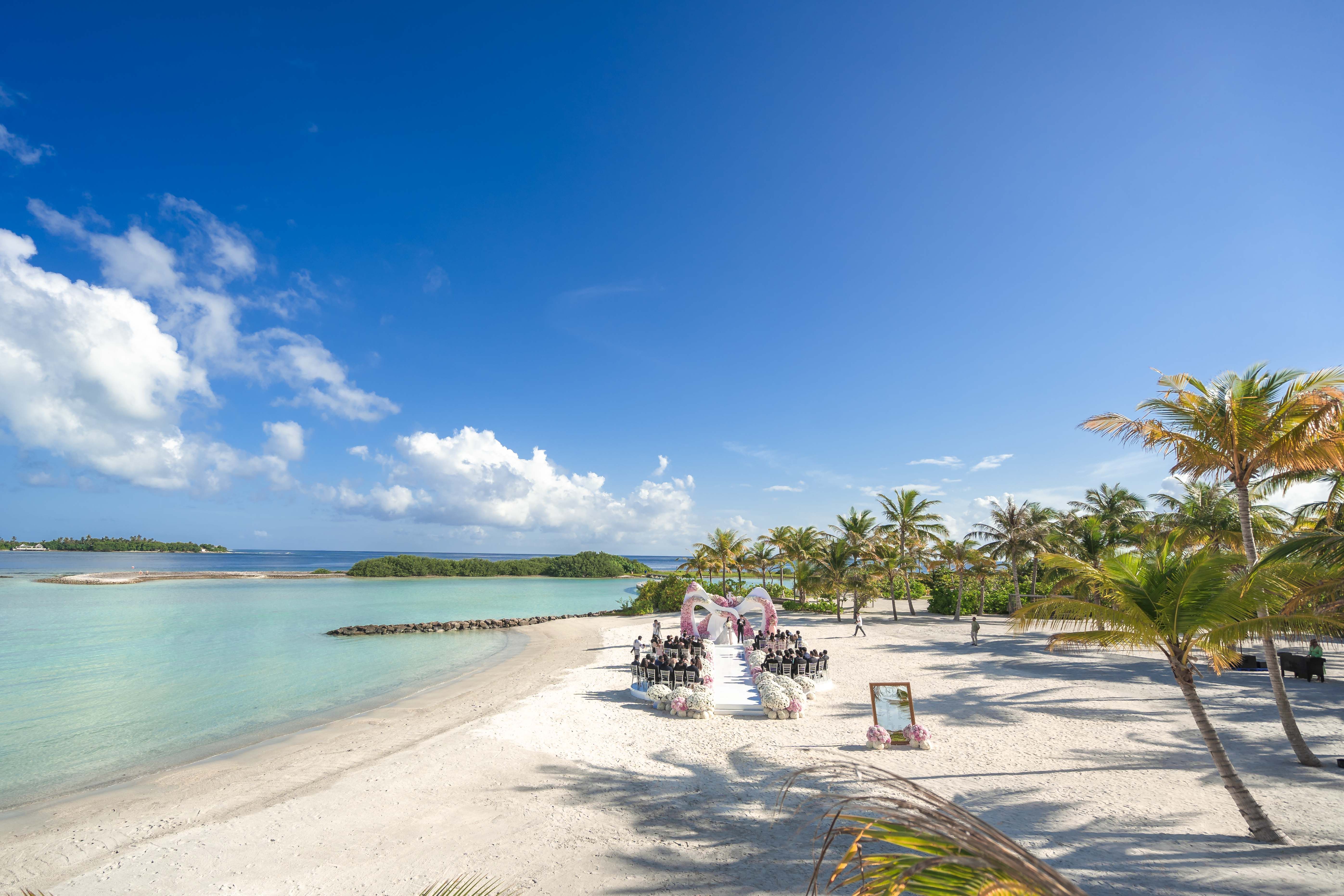 Beautiful tropical beach wedding venue setup with palm trees under blue sky