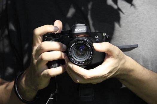 Close-up shot of hands holding a DSLR camera outdoors.