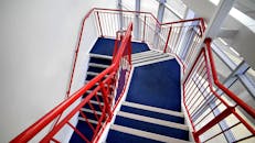 室内楼梯配有红色栏杆和蓝色地毯，体现了现代建筑设计风格