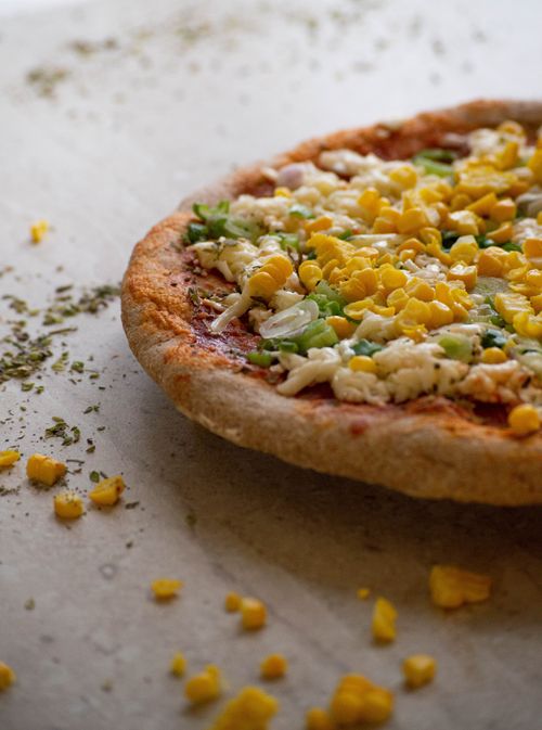 Free Appetizing close-up of a fresh pizza topped with corn, cheese, and herbs, perfect for food photography. Stock Photo