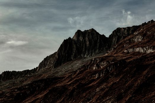 A rugged rocky mountain under a dramatic sky with striking formations and textures.