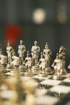 Detailed close-up of a silver Roman-themed chess set with ornate pieces on the board.