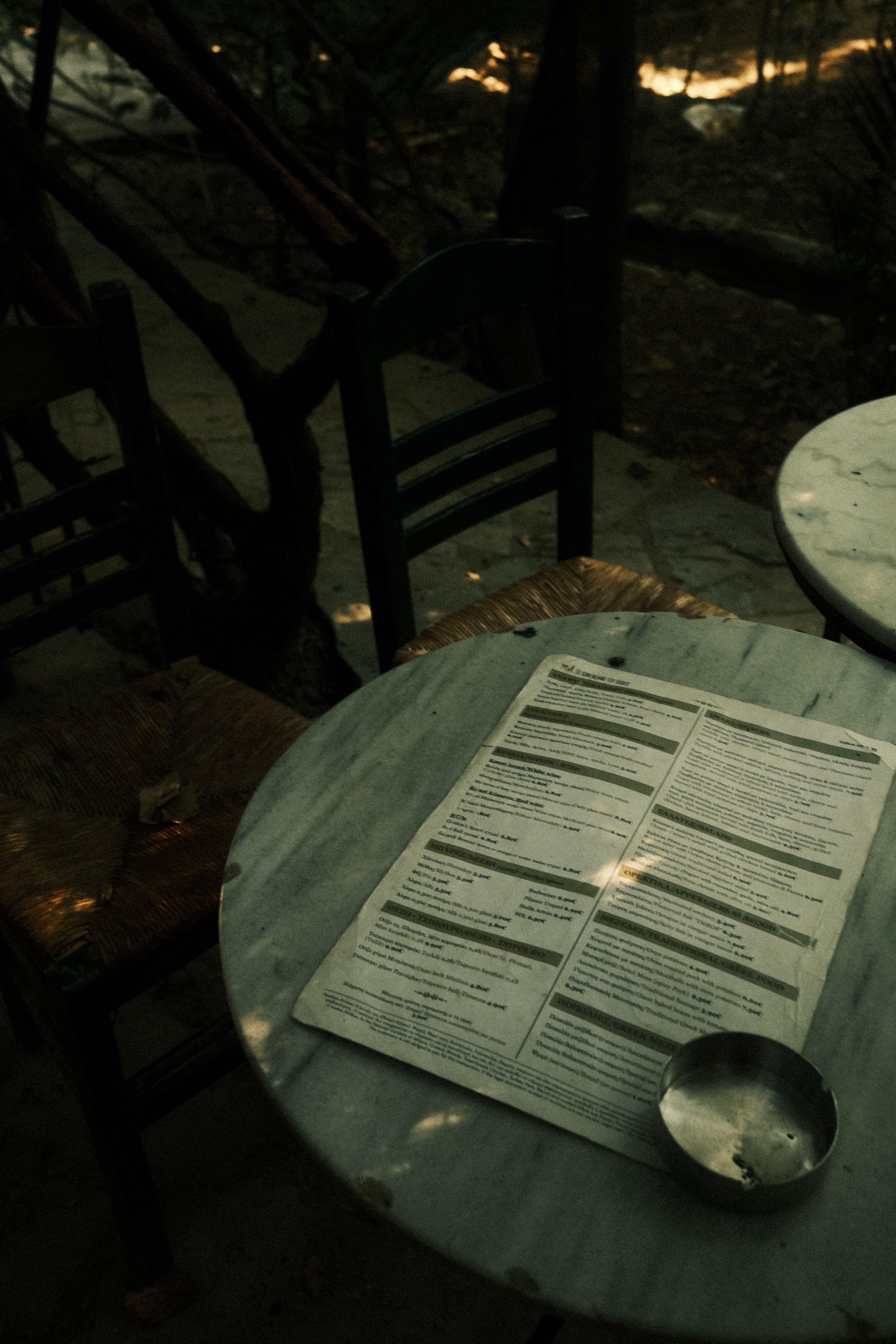 Shadowy outdoor cafe setting with menu on a marble table.
