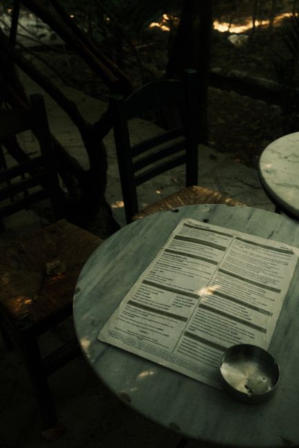 Shadowy outdoor cafe setting with menu on a marble table.