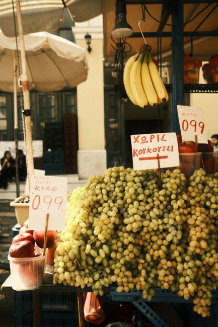 Vibrant arrangement of grapes and bananas at an outdoor market stall.