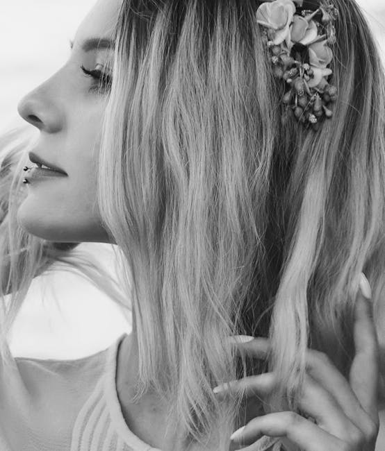 Artistic side view portrait of a woman with a floral hairpiece, emphasizing her lip piercing and serene expression.