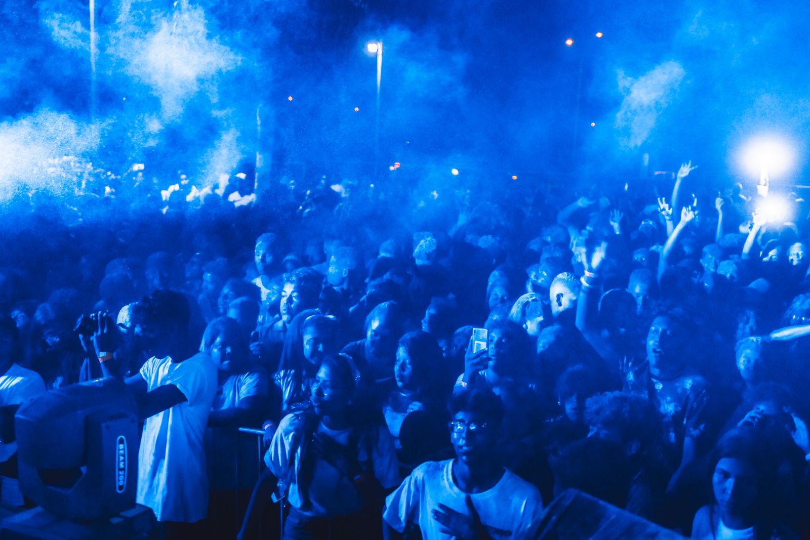 A concert crowd under blue stage lighting