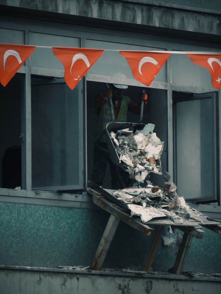 Worker Throwing Trash From Cart On Building Site