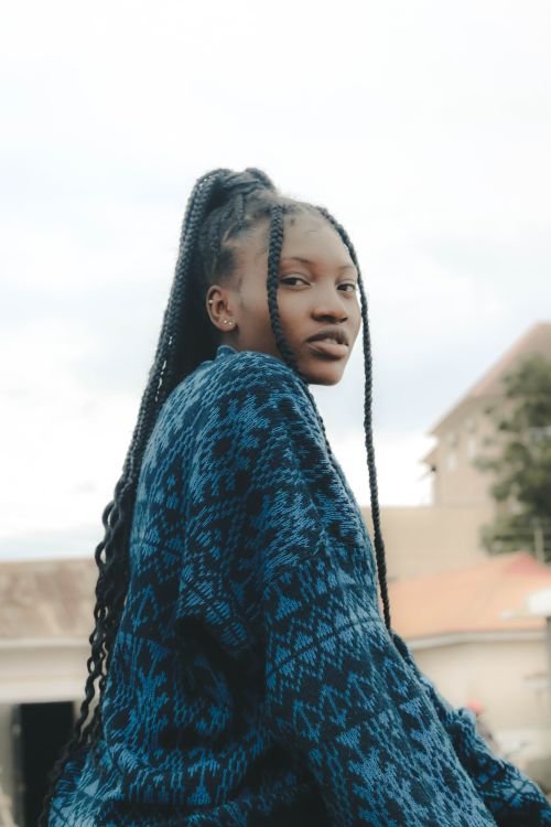 Free Stylish portrait of a woman with long braided hair wearing a patterned sweater outdoors. Stock Photo