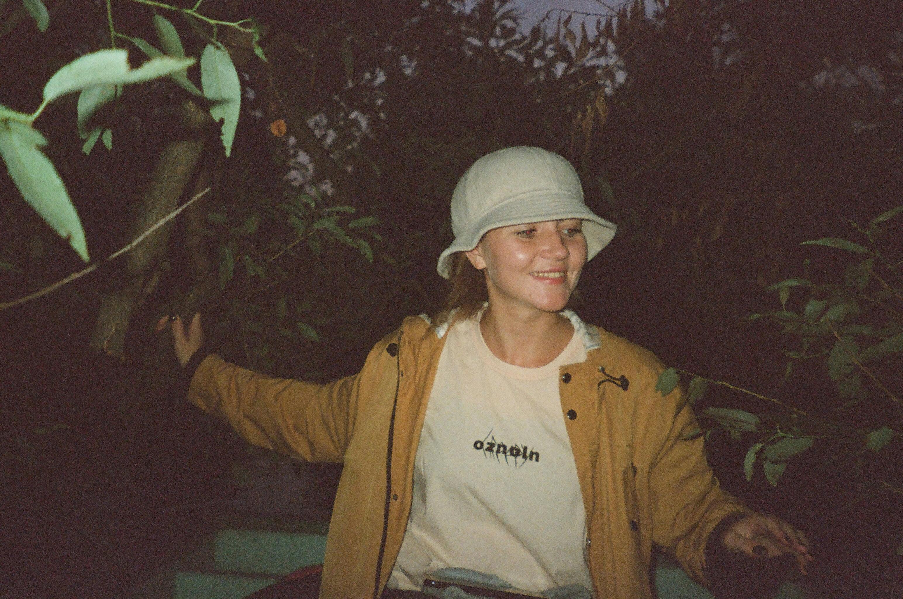 一位戴着帽子、穿着夹克的妇女在森林中散步，面带微笑