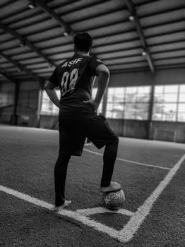 Monochrome photo of a soccer player standing on a football field in Dhaka, Bangladesh.