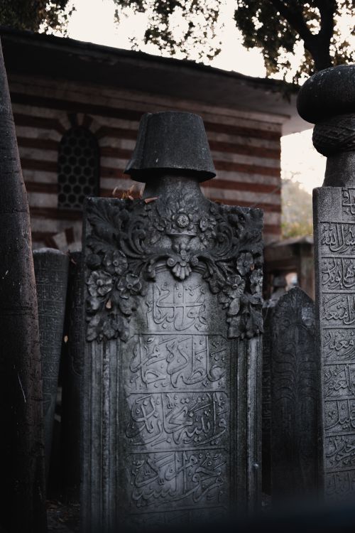 Free Detailed view of ornate tombstones with Arabic inscriptions in a tranquil Islamic cemetery setting. Stock Photo