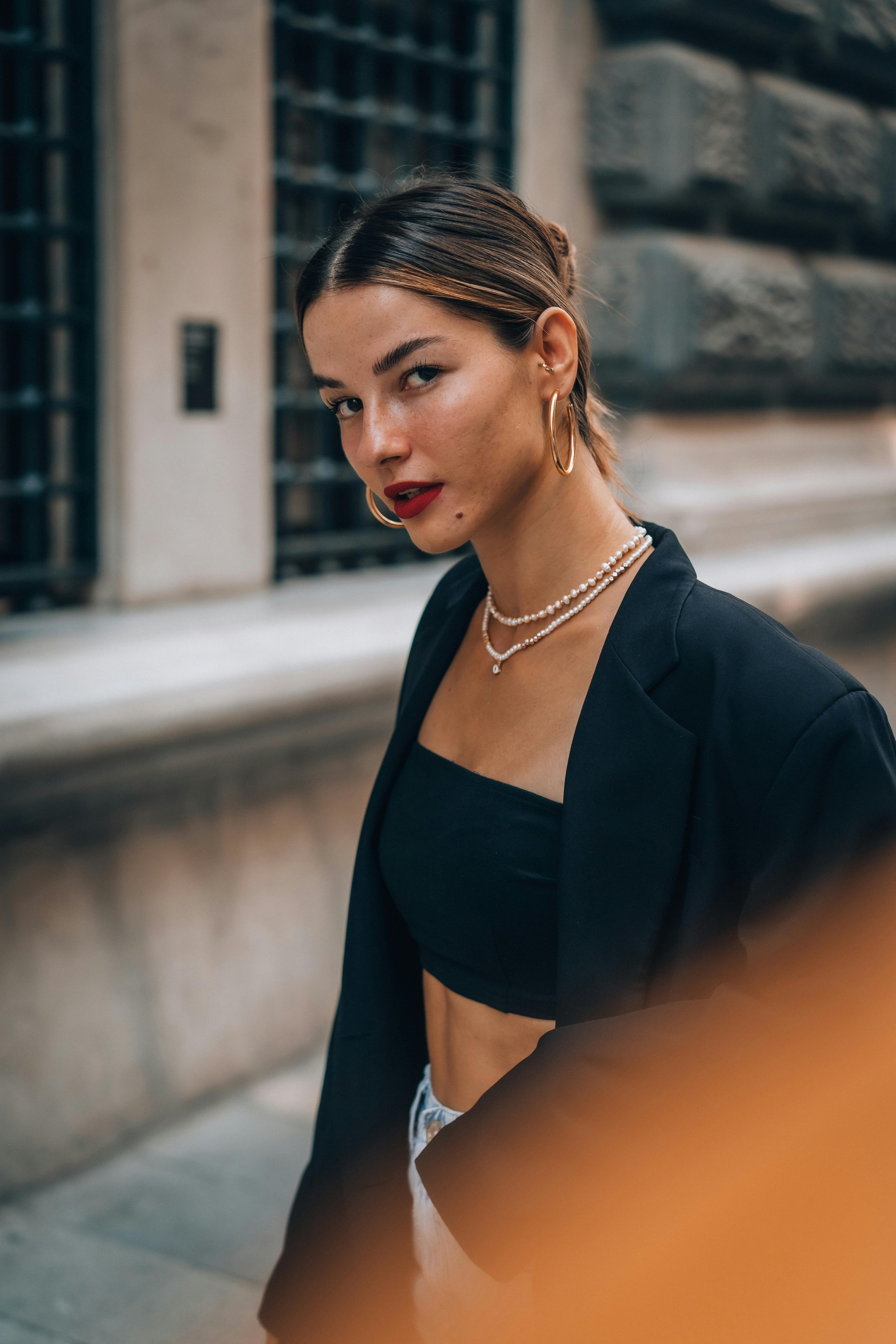 Fashionable woman wearing pearls and a blazer in an urban environment, exuding elegance.