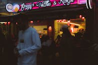 A Man in White Long Sleeve Shirt Walking on the Street During Night Time