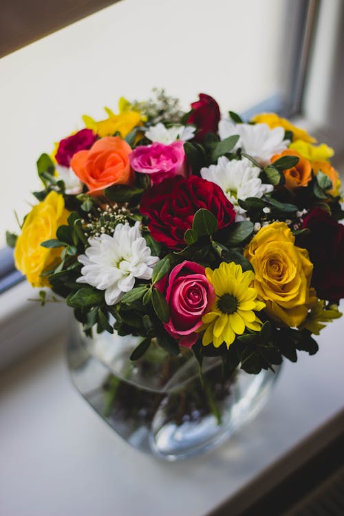 Free Mums and Rose Flower in Clear Glass Vase Centerpiece Beside Glass Window Stock Photo