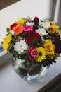 Mums and Rose Flower in Clear Glass Vase Centerpiece Beside Glass Window