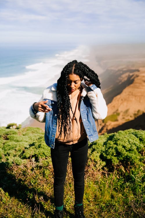 Woman in Blue Denim Jacket Standing on a Cliff