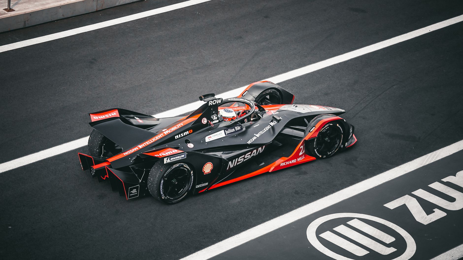 High-speed Formula E car on the circuit in Ciudad de México, captured during a daytime motorsport event.