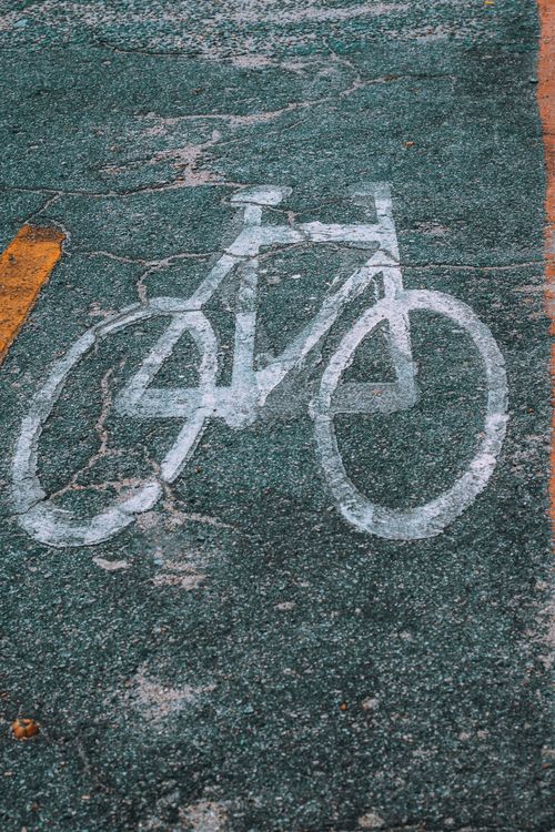 Free White bicycle symbol on textured asphalt road, marking a dedicated bike lane. Stock Photo